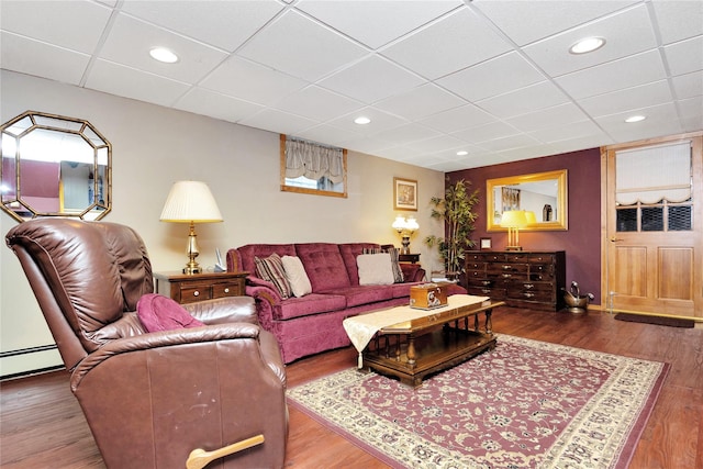 living room with a drop ceiling and wood-type flooring