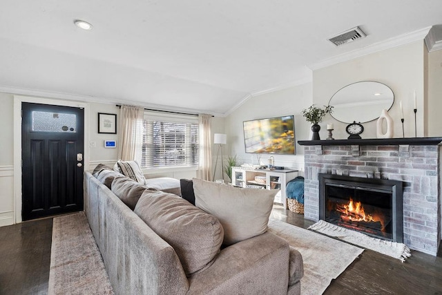 living room with crown molding, lofted ceiling, a brick fireplace, and hardwood / wood-style flooring