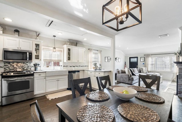 dining space featuring a healthy amount of sunlight, sink, crown molding, and dark hardwood / wood-style flooring