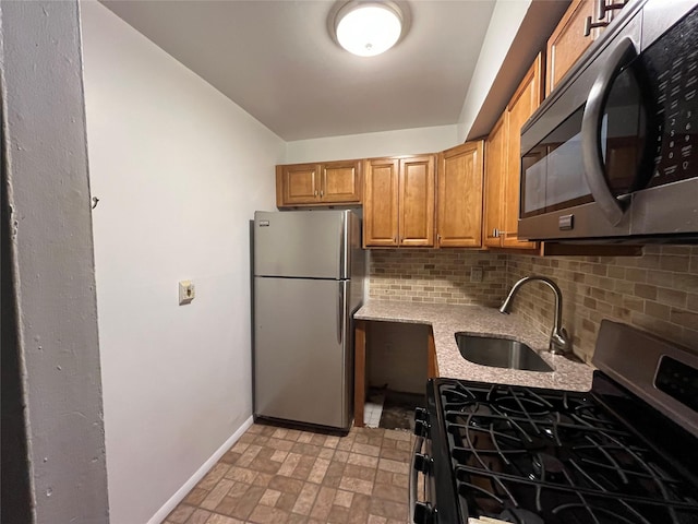 kitchen featuring decorative backsplash, sink, light stone counters, and appliances with stainless steel finishes