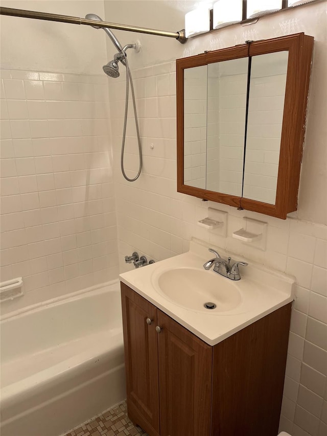 bathroom featuring decorative backsplash, tile walls, vanity, and tiled shower / bath