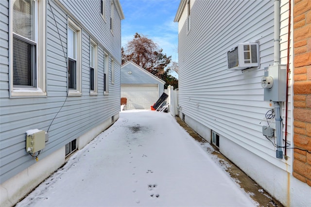 snow covered property featuring a garage and an outbuilding