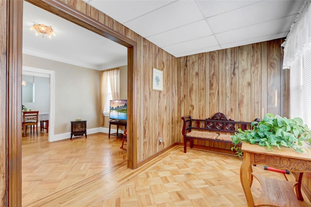 sitting room with crown molding, parquet flooring, wooden walls, and a drop ceiling