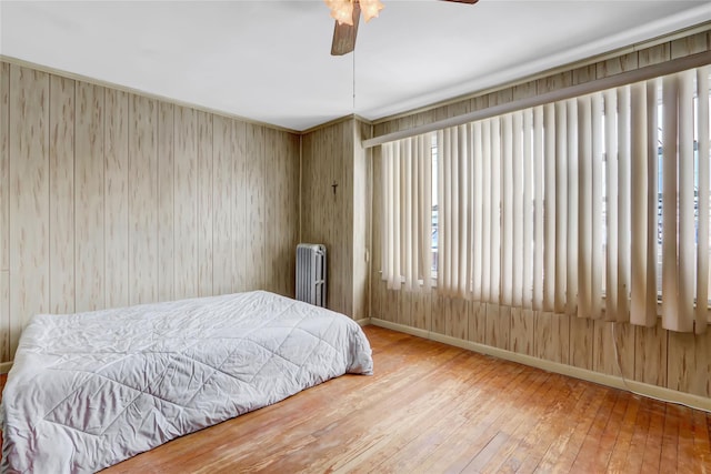 bedroom featuring wood-type flooring, radiator, and ceiling fan