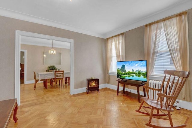 living area featuring baseboards, a chandelier, and crown molding