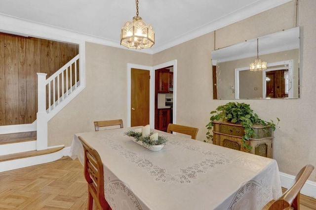 dining space featuring a chandelier, crown molding, stairway, and baseboards