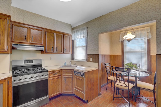 kitchen featuring stainless steel gas stove, under cabinet range hood, and wallpapered walls