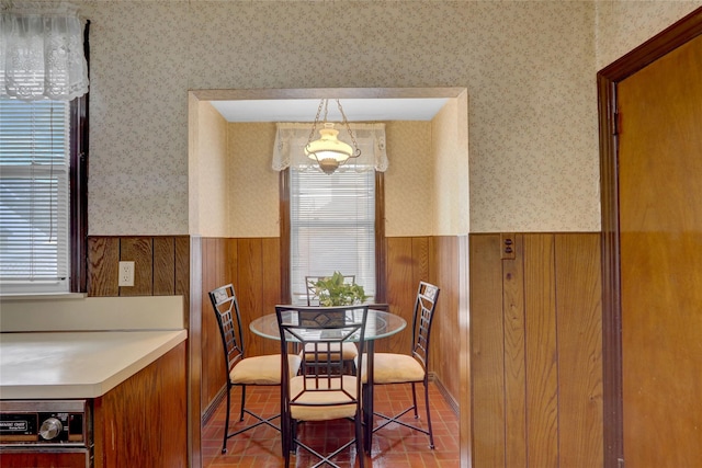 dining area featuring a wealth of natural light, a wainscoted wall, and wallpapered walls