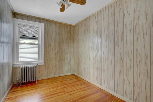 spare room featuring baseboards, radiator heating unit, a ceiling fan, and wood finished floors