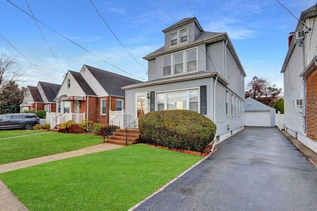 american foursquare style home featuring aphalt driveway, a detached garage, a front lawn, and an outdoor structure