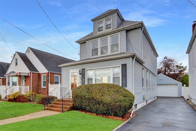 american foursquare style home featuring a garage, an outdoor structure, and a front lawn