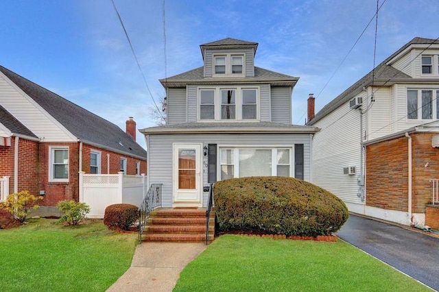 american foursquare style home with fence, a front lawn, and a wall mounted AC