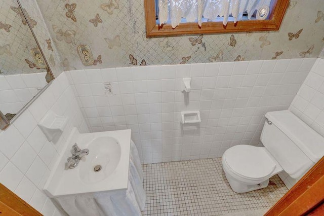 bathroom featuring tile patterned flooring, a wainscoted wall, toilet, and wallpapered walls