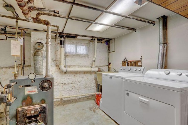 laundry room featuring laundry area, water heater, washer and clothes dryer, and a sink