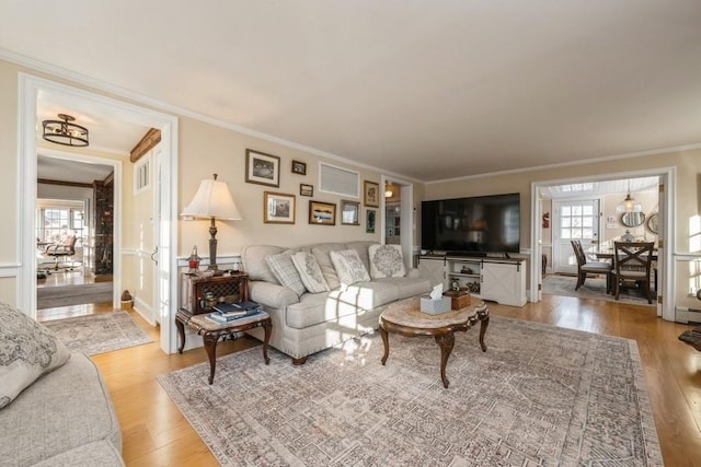 living room with a wealth of natural light, ornamental molding, and light hardwood / wood-style flooring