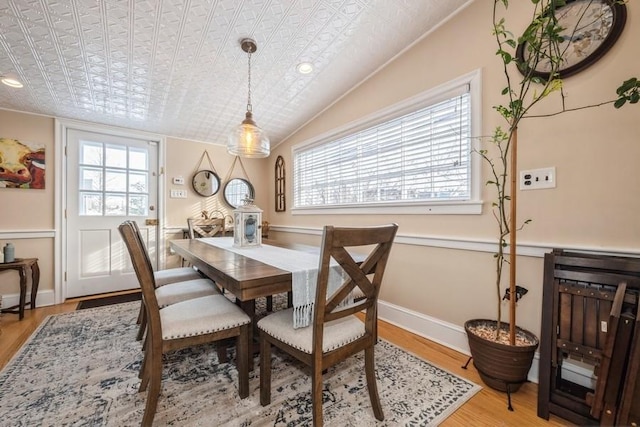 dining space with light hardwood / wood-style floors, a wealth of natural light, and lofted ceiling