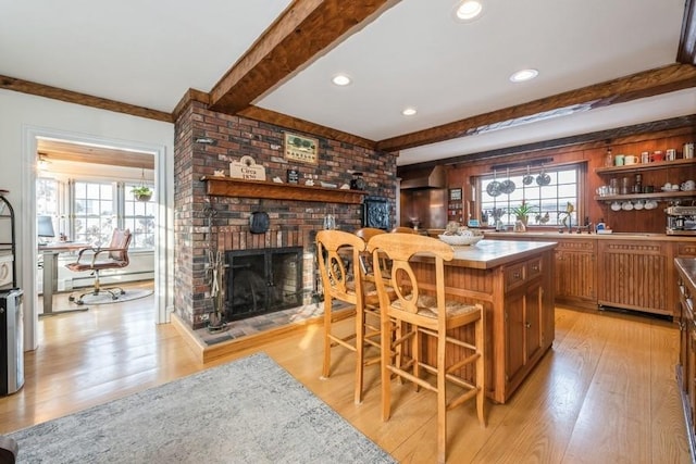 bar with light hardwood / wood-style floors, a baseboard heating unit, a brick fireplace, and beamed ceiling