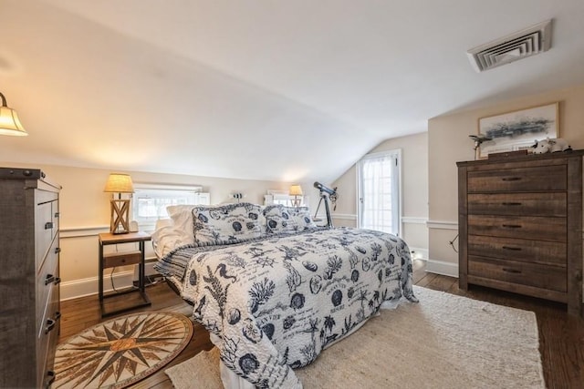 bedroom with vaulted ceiling, dark wood-type flooring, and multiple windows