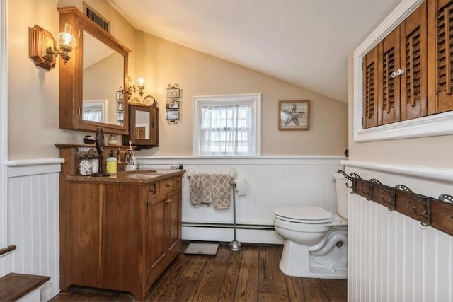 bathroom featuring baseboard heating, lofted ceiling, wood-type flooring, vanity, and toilet