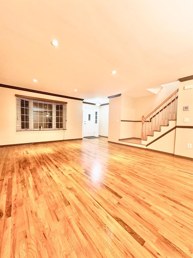 unfurnished living room with ornamental molding and light hardwood / wood-style floors