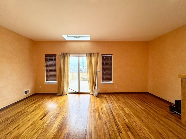 spare room featuring light wood-type flooring and a skylight