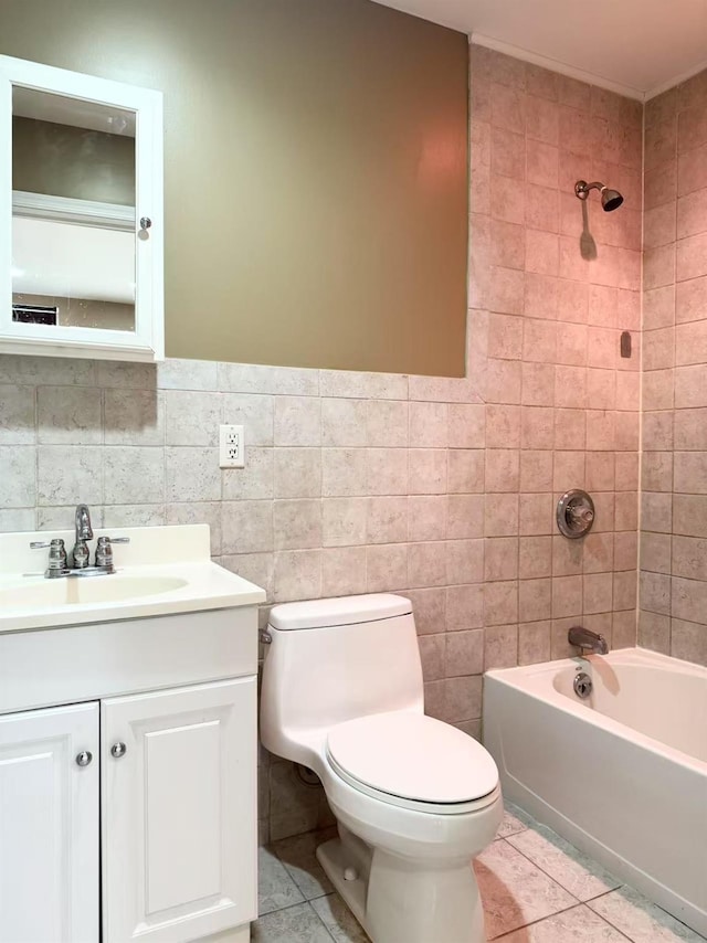 full bathroom with tile walls, tiled shower / bath combo, vanity, toilet, and tile patterned floors