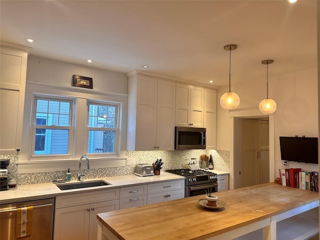 kitchen with sink, white cabinets, stainless steel appliances, and wood counters