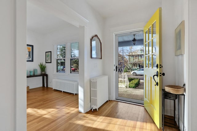 foyer entrance with hardwood / wood-style flooring and radiator heating unit