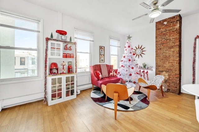 sitting room with light wood-type flooring, ceiling fan, and a baseboard radiator