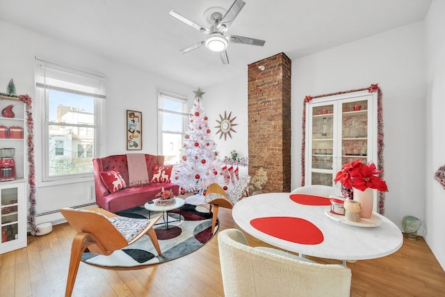 dining space with ceiling fan, plenty of natural light, a baseboard radiator, and hardwood / wood-style flooring