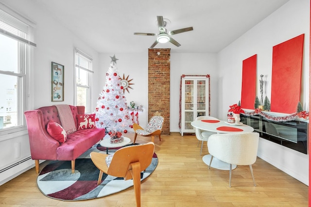 sitting room featuring ceiling fan, light wood-type flooring, plenty of natural light, and baseboard heating