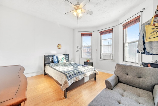 bedroom with ceiling fan, light hardwood / wood-style floors, and a textured ceiling