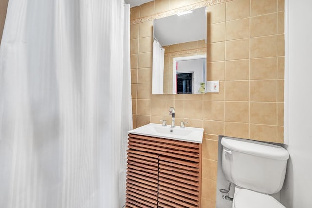 bathroom with toilet, vanity, tile walls, and decorative backsplash