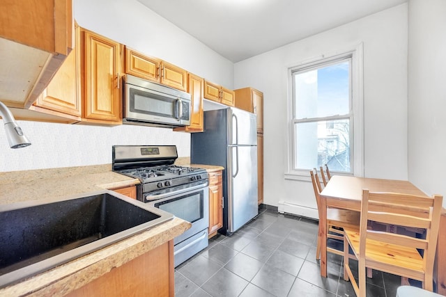 kitchen featuring appliances with stainless steel finishes, tasteful backsplash, baseboard heating, dark tile patterned floors, and sink