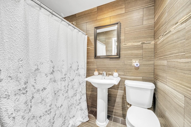 bathroom featuring toilet, tile walls, sink, and a shower with shower curtain