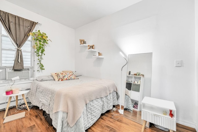 bedroom featuring a baseboard radiator, wood-type flooring, and cooling unit