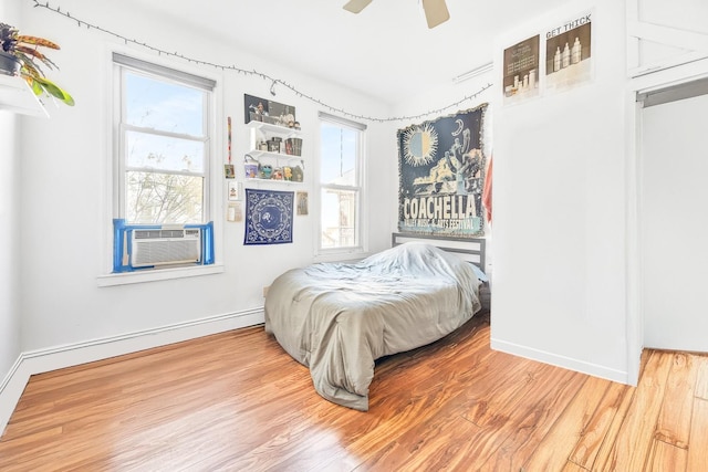 bedroom with ceiling fan, cooling unit, and hardwood / wood-style flooring