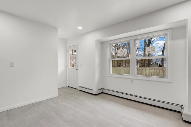 empty room featuring baseboard heating and a healthy amount of sunlight