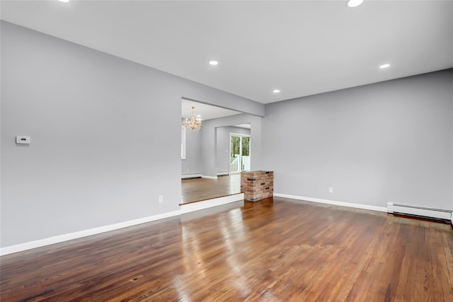 spare room featuring a baseboard radiator, wood-type flooring, and an inviting chandelier