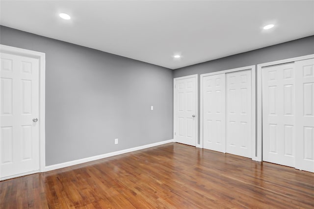 unfurnished bedroom with dark wood-type flooring and two closets