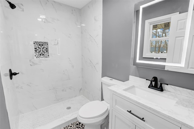 bathroom with toilet, vanity, and tiled shower