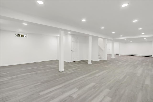 basement with a baseboard heating unit and light wood-type flooring