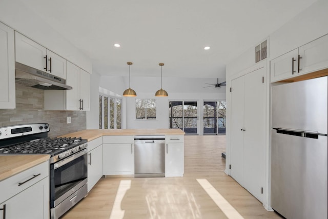 kitchen featuring tasteful backsplash, appliances with stainless steel finishes, white cabinets, and hanging light fixtures