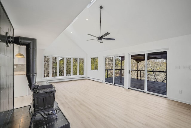 interior space featuring ceiling fan, a wood stove, hardwood / wood-style floors, and high vaulted ceiling