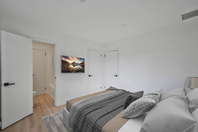 bedroom with light wood-type flooring and connected bathroom