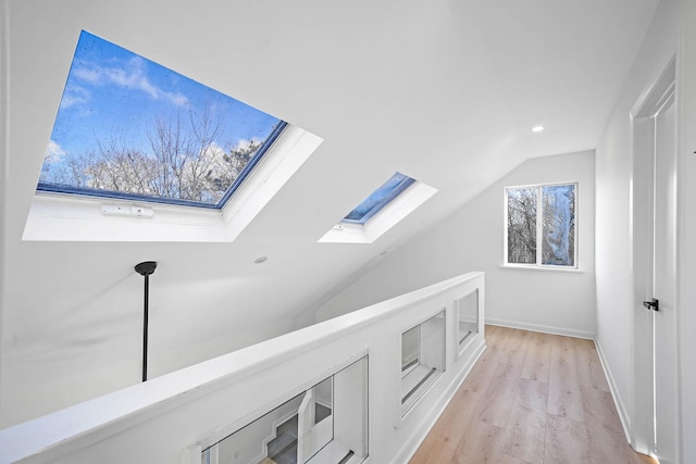 bonus room with vaulted ceiling with skylight, a wealth of natural light, and light hardwood / wood-style flooring