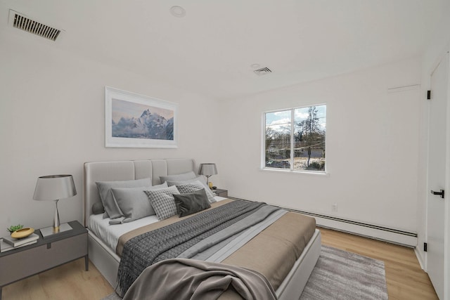 bedroom with light hardwood / wood-style floors and a baseboard radiator