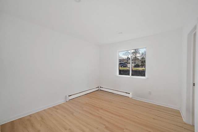 spare room featuring baseboard heating and light hardwood / wood-style flooring