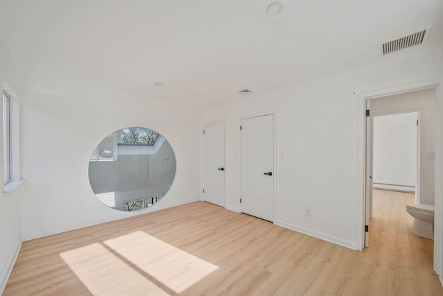 unfurnished bedroom featuring ensuite bath and light wood-type flooring