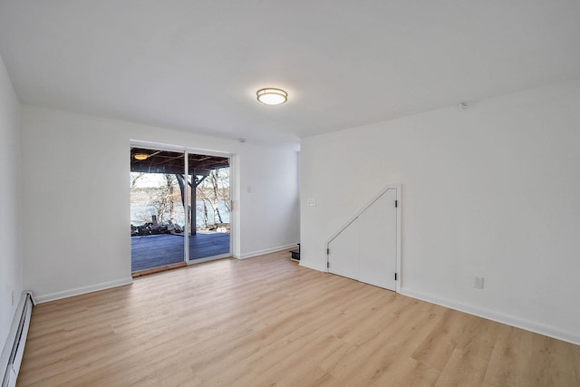 spare room with a baseboard heating unit and light wood-type flooring